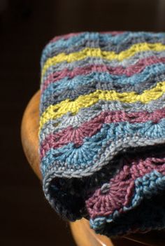 a crocheted blanket sitting on top of a wooden chair