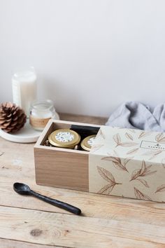 an open box with two cookies in it on a wooden table next to a candle