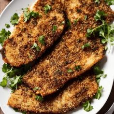 three pieces of fish on a white plate with parsley sprinkled on top