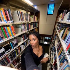 a woman standing in front of a bookshelf filled with lots of book's