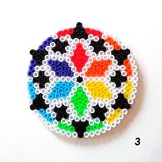 a colorful beaded brooch sitting on top of a white table next to a ruler