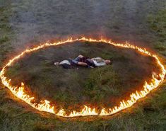 two people laying in the middle of a circle of fire