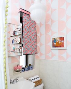 a bathroom with pink and white wallpaper has a toilet, sink, and shelving unit