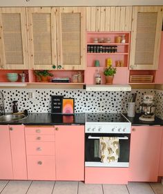 a kitchen with pink cabinets and black counter tops, including a stove top oven in the center