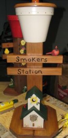 there is a small birdhouse on top of a wooden stand that says smokers station