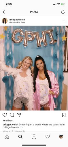 two women standing next to each other in front of a photo booth with balloons and streamers