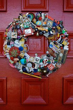 a red door with a wreath made out of many different items on it's side