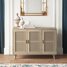 a white and gold sideboard in front of a mirror on a wall with blue curtains