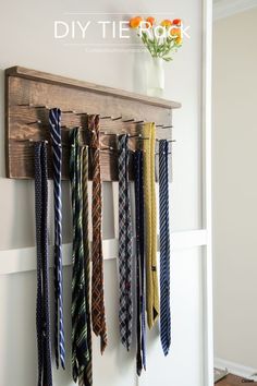 several ties are hanging on the wall in front of a vase with an orange flower