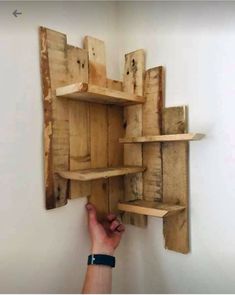 a person is placing wooden shelves on the wall to display items that are made out of pallet wood