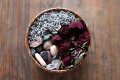 a bowl filled with rocks and flowers on top of a wooden table