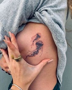 a woman holding her stomach with a tattoo on it