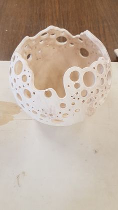 a white bowl sitting on top of a table next to a wooden table with scissors