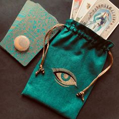 a green bag with an eye on it next to some cards and a coin purse