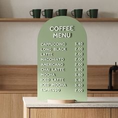 a green sign sitting on top of a counter next to cups and coffee mugs