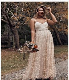 a pregnant woman in a dress is standing on the road with her hands behind her head