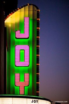 a large neon sign that says joy on it's side in front of a building