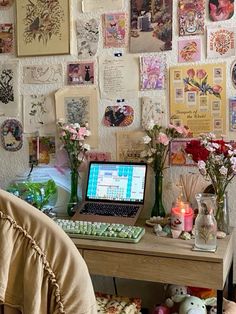 a laptop computer sitting on top of a wooden desk covered in pictures and pink flowers