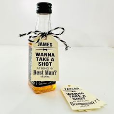 a bottle of whiskey sitting on top of a table next to a tag that says, james wanna take a shot at being my best man?