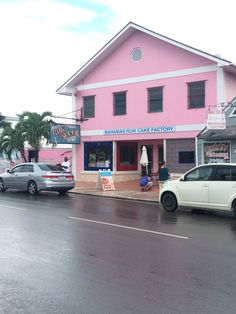 a pink building on the side of a road with cars parked in front of it