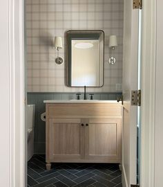 a bathroom with a sink, mirror and toilet paper roll on the wall next to it