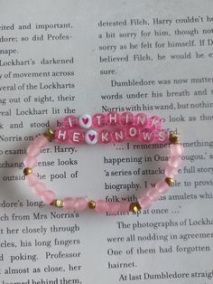 two pink bracelets with words on them sitting on top of an open book page