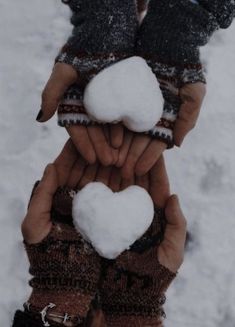 two hands holding snowballs in the middle of their palms, with one heart on it