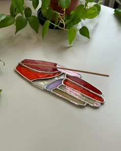 a stained glass piece sitting on top of a table next to a potted plant