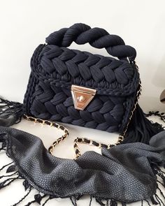 a black handbag sitting on top of a table next to a scarf and shoes