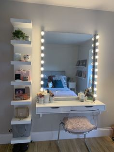 a white vanity with lights on it and a bed in the background