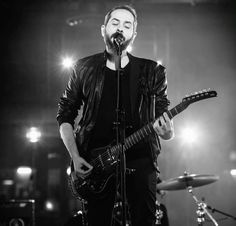 a man standing in front of a microphone while holding a guitar