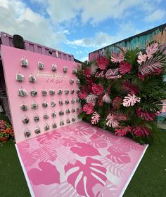 a pink and white calendar sitting on top of a grass covered field next to flowers