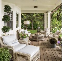 a porch with wicker furniture and potted plants