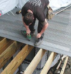 a man working on the roof of a house with wood planks in front of him