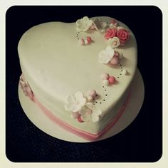 a white heart shaped cake with pink and white flowers