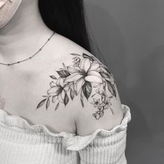 a woman's shoulder with flowers and leaves on the back of her body,