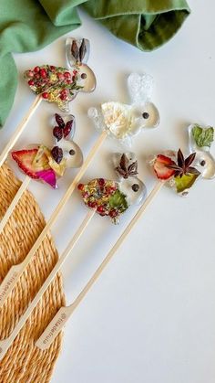 several wooden spoons with fruit on them sitting next to a green cloth and some other items