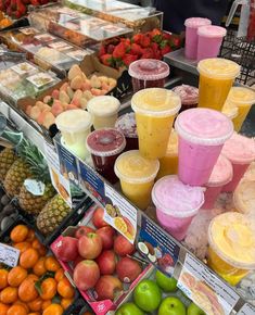 there are many fruits and smoothies on display at this market stall, including oranges, strawberries, apples, lemonade, and more