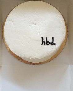 a white frosted cake with the word hbd written on it in cursive writing