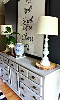 a white dresser sitting in a living room next to a lamp