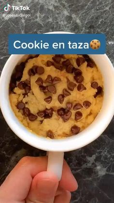 a hand holding a cup filled with cookie en taza