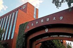 an arch in front of a building with chinese writing on it and trees growing up the side