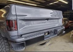 the back end of a silver truck parked in a garage