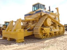 a large yellow bulldozer sitting on top of a dirt field