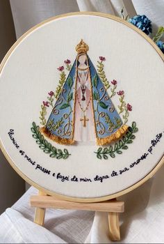 a cross - stitch embroidered onto a wooden easel with an image of the virgin mary