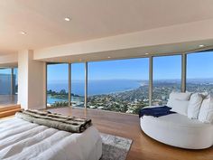 a bedroom with large windows and a white bed in front of a window overlooking the ocean