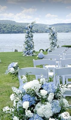 rows of white chairs with blue and white flowers on the grass at a wedding ceremony