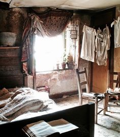 an old bedroom with clothes hanging from the ceiling