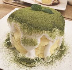 a green cake with white icing and sprinkles sits on a plate