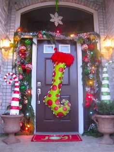 a decorated front door with christmas stockings and candy canes on the outside, along with potted plants